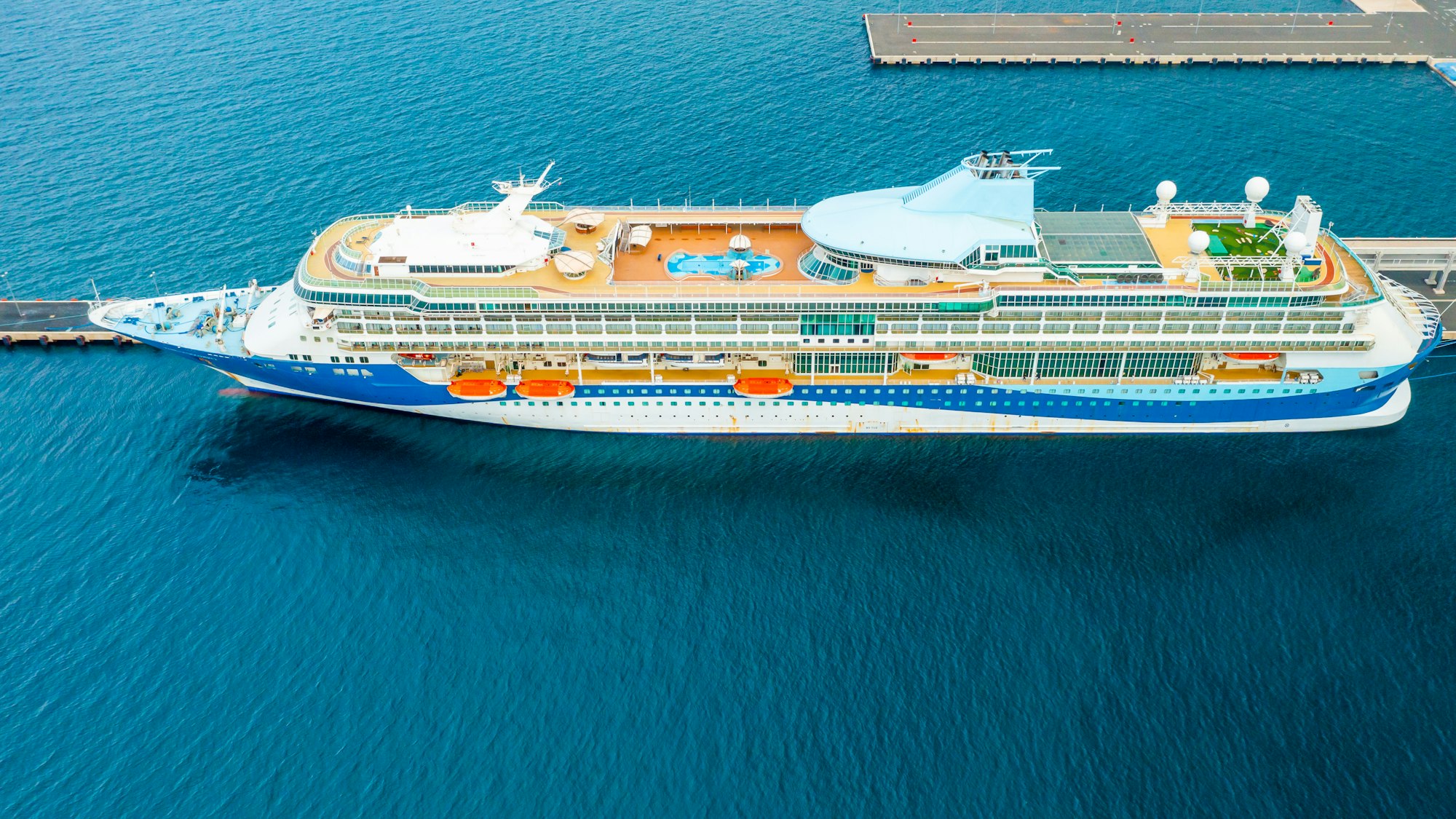 Aerial view of a luxury cruise ship or linear with a swimming pool on the roof moored in marina