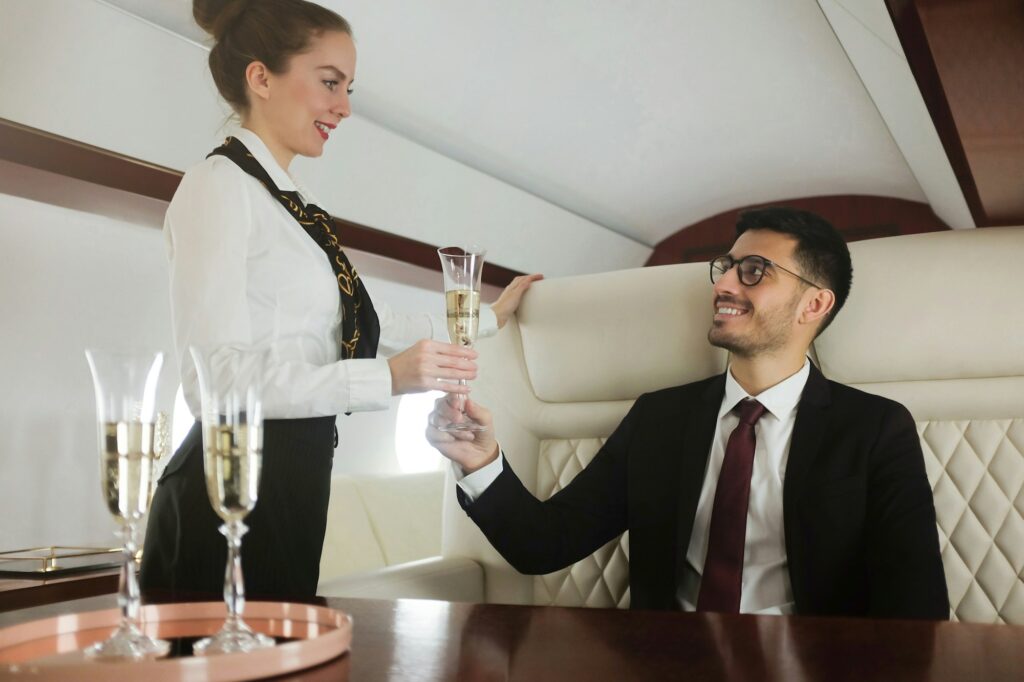 Young billionaire travelling first class, flight attendant is bringing him glass of champagne